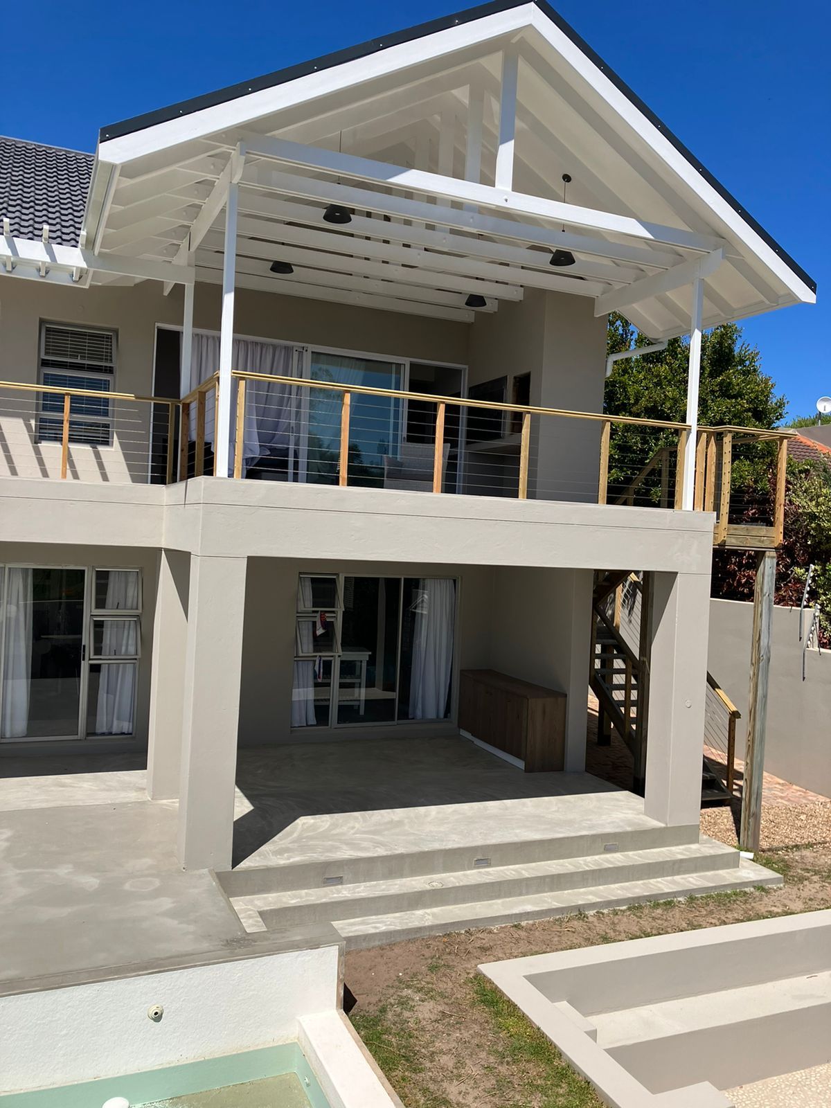 Plettenberg Bay house after alteration — double-storey covered decks under a white gable