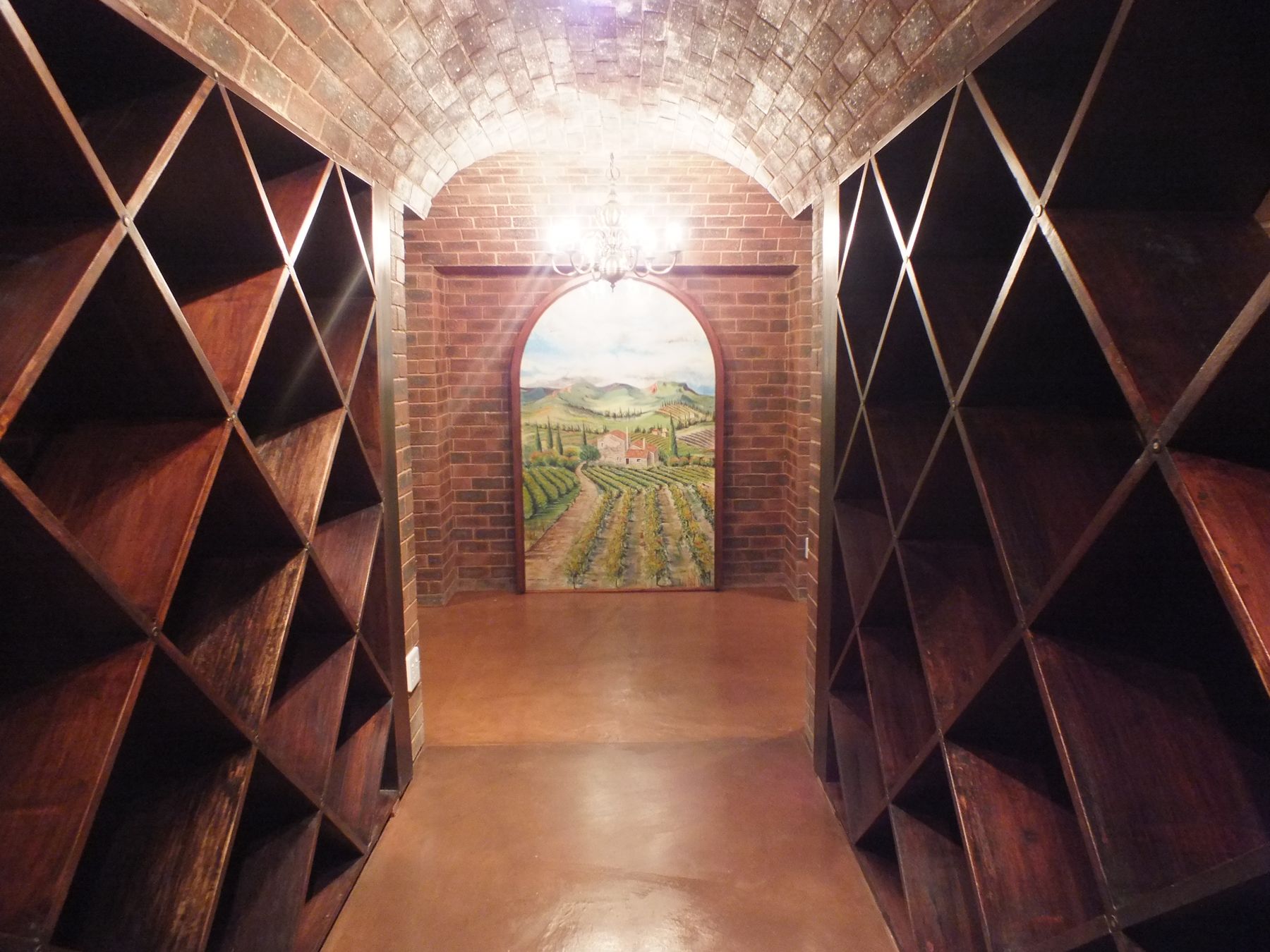 Arched vineyard mural at the end of a brick-vaulted wine cellar in Glenadrienne