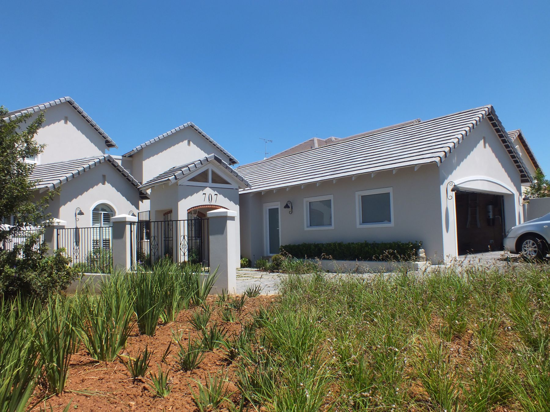 New house in Cedar Lakes with a row of arched gables behind an indigenous garden