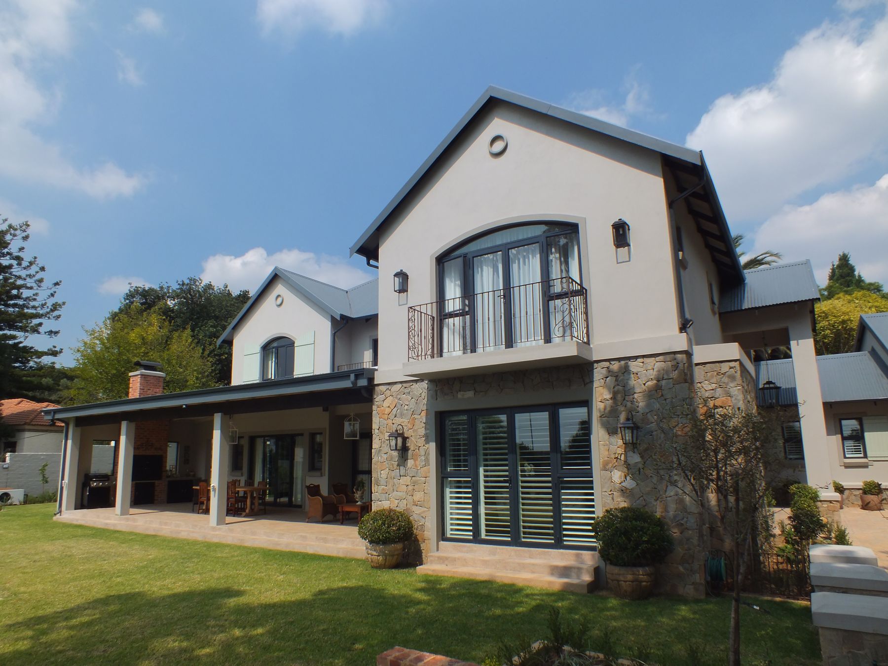 New house in Northcliff — gabled wing over a stone-clad base with covered patio